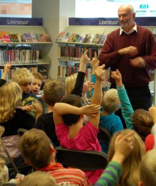 Schrijver Kees Opmeer met groep kinderen in bibliotheek